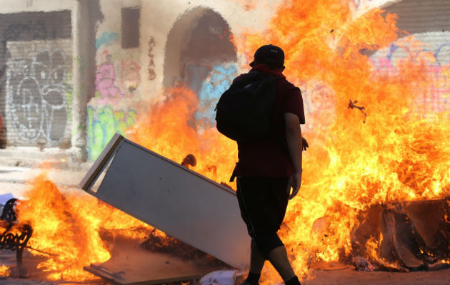 Un millón de personas marchan en Chile contra Piñera y la desigualdad social Encapuchados montan barricadas frente a la policía tras manifestarse en el centro de Santiago. Foto: EFE.