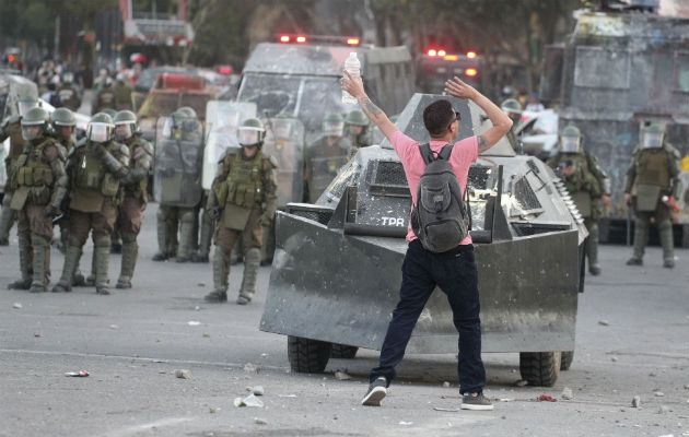 Policía de Chile suspende de manera temporal uso de perdigones en protestas Manifestante chileno frente a policías antidisturbios en Santiago. Foto: AP.