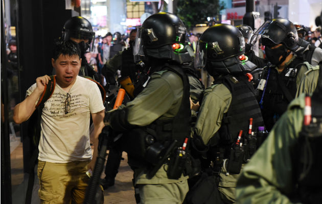 Violentos choques en Hong Kong entre la Policía y grupos de manifestantes Un hombre afectado por gas pimienta camina ante policías antidisturbios. Foto: EFE.
