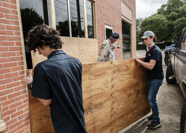 Miles evacuan en EE.UU. ante el "catastrófico" impacto del huracán Laura Un padre y su hijo colocan tablones en su local comercial en Louisiana. Fotos: EFE.
