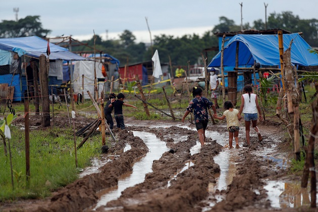 Niños recorren un camino lodoso en el terreno "Victoriano Lorenzo", en el sector de la 24 de Diciembre. Foto: EFE Niños recorren un camino lodoso en el terreno "Victoriano Lorenzo", en el sector de la 24 de Diciembre. Foto: EFE