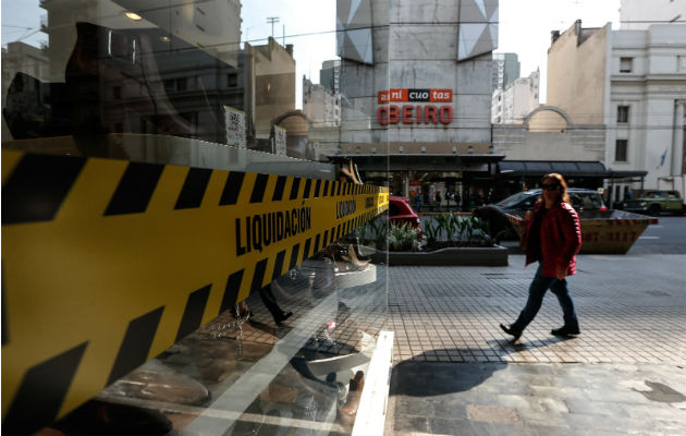¡Crisis!, Argentina formaliza congelación de precios de combustibles por 90 días Una mujer pasa frente a un negocio con aviso de liquidación, en Buenos Aires (Argentina). Foto: EFE.