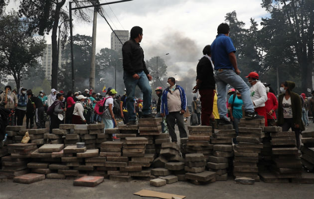 El presidente de Ecuador decreta toque de queda desde las 20.00 GMT en Quito Manifestantes tras una barricada de piedras que bloquea una calle este sábado, en Quito. Foto: EFE.