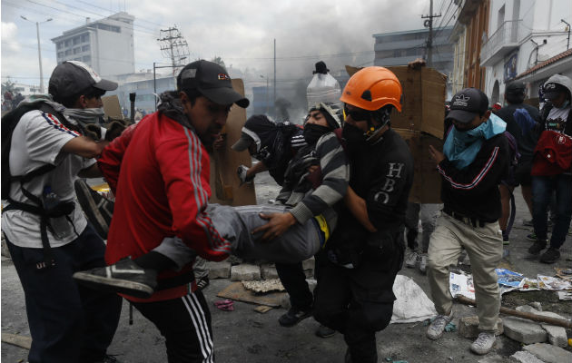 El presidente de Ecuador decreta toque de queda desde las 20.00 GMT en Quito Manifestantes tras una barricada de piedras que bloquea una calle este sábado, en Quito. Foto: EFE.