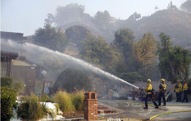 Los fuegos en California se cobran una vida y amenazan a 100.000 casas Bomberos combaten el fuego en una casa en "Porter Ranch", California. Foto: AP.
