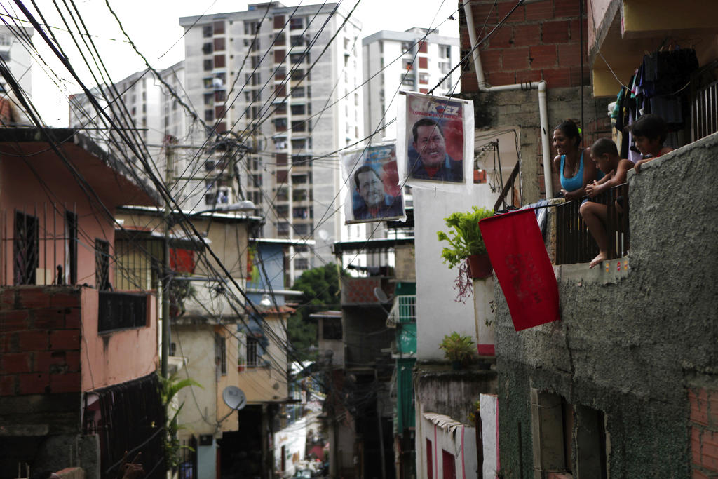 Una familia se reúne en su balcón cerca carteles del presidente Chávez, en el barrio de Petare de Caracas. AP<br>