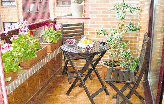Terraza pequeña con mesa redonda y macetas