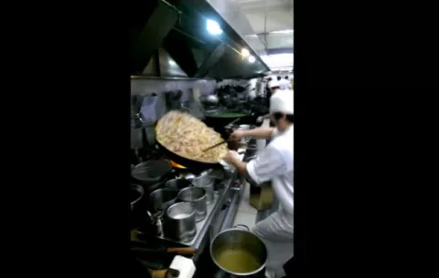 El cocinero con su impresionante destreza con el wok