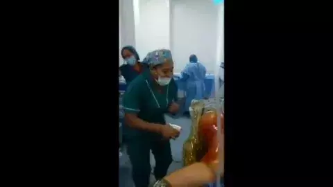 Enfermeras bailan y ríen alrededor de una paciente anestesiada