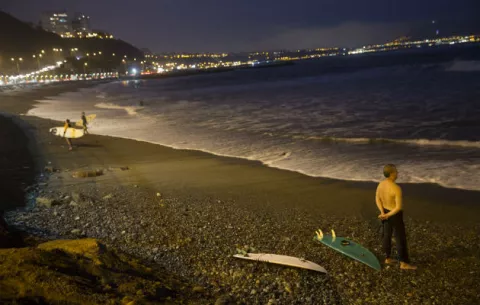 Surfistas nocturnos corren olas en playa de Lima 
