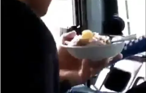 Conductor es captado manejando y sosteniendo un plato de comida en la mano