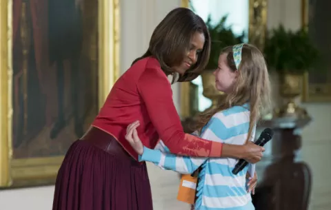 Una niña entrega a Michelle Obama el currículum de su padre desempleado