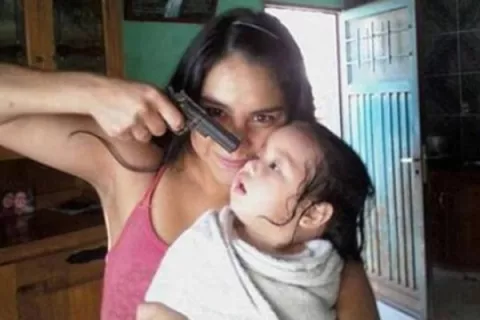 Se toma foto apuntándole con una pistola el rostro de una bebe 