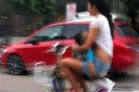 Da pecho a su hijo de meses mientras  conducía una moto en China