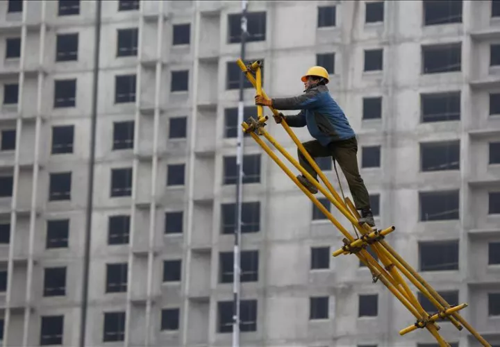 Un obrero trabaja sobre un andamio para encofrado en las obras de construcción de un edificio dePekín. Foto:EFE