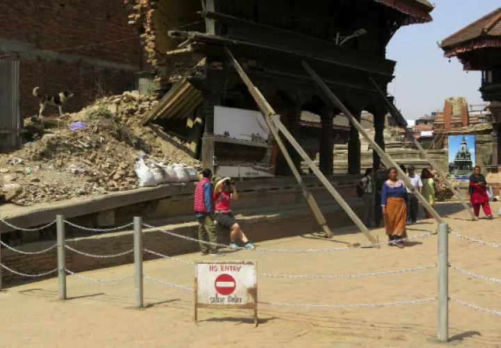 Una turista trata de fotografiar un monumento en Bakhtapur, destruída por un terremoto. Foto/EFE