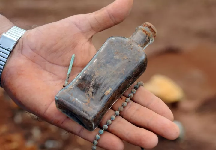 Botella de vidrio y cadena halladas en trabajos de excavación.    