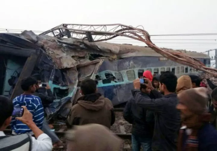 Varias personas toman fotografías con sus celulares del sitio del accidente donde un tren de Aimer-Sealdah Express se descarriló hoy, en Kanpur (India). Foto: EFE