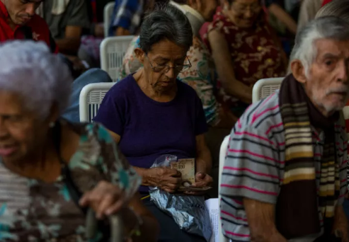 Los adultos mayores organizan sus billetes de 100 bolívares. FOTO/EFE