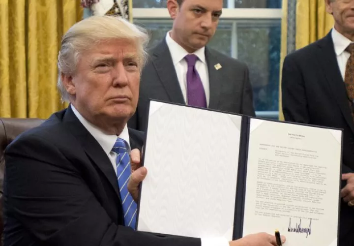 El presidente Donald Trump muestra el documento que firmó sobre el TPP. AP