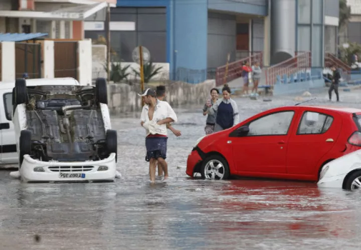 - Varias personas observan vehículos averiados por las inundaciones, en La Habana. FOTO/EFE 