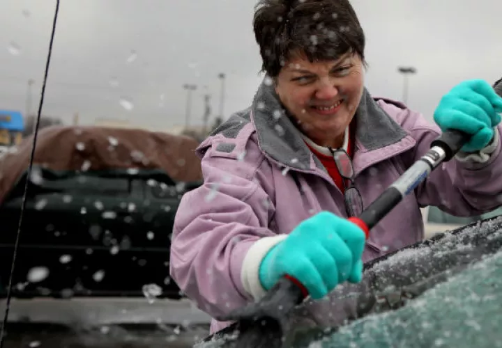 Una mujer quita el hielo de su auto. FOTO/AP