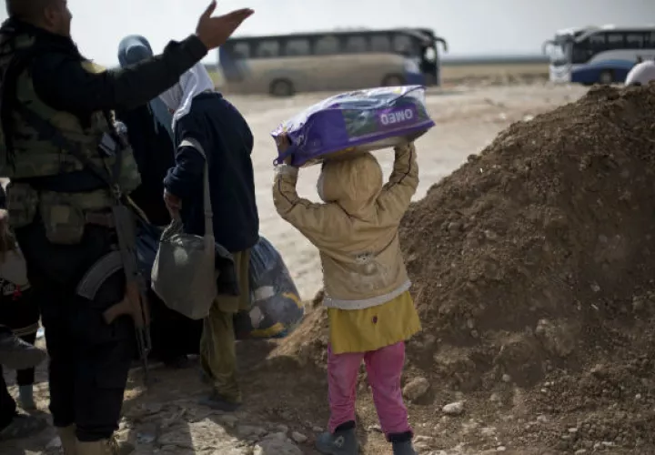 Una niña de Mosul lleva una manta mientras su familia busca permiso para pasar por un puesto de control en Bartella, Irak. FOTO/AP