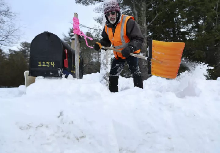 Un hombre quita la nieve de la puerta de su casa. FOTO/AP