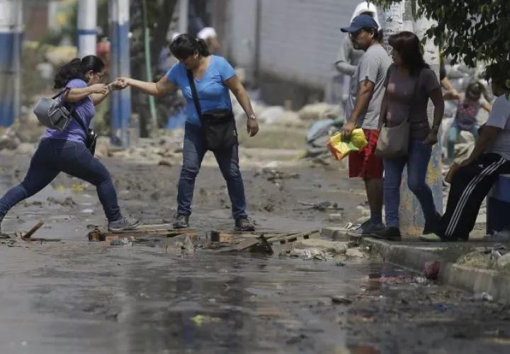Los peruanos tienen que pasar por calles inundadas. /Foto AP