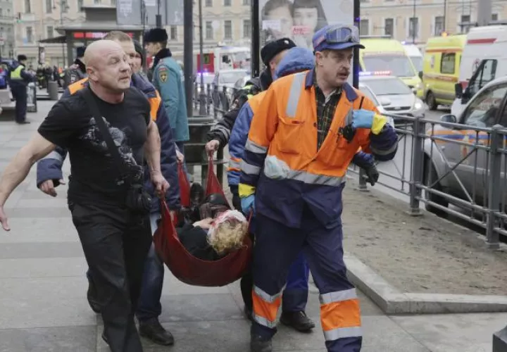 Bomberos y trabajadores de los servicios de emergencias transportan a una mujer. EFE