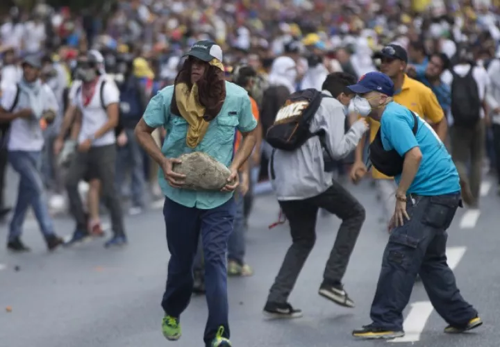 Un grupo de manifestantes huye de los gases lacrimógenos. /Foto AP