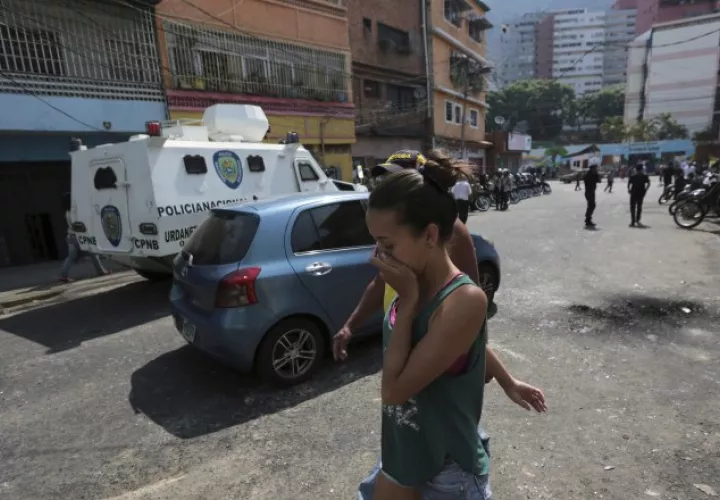 Una joven se cubre la nariz afectada por gases lacrimógenos tirados por la Policía Bolivariana. /Foto AP