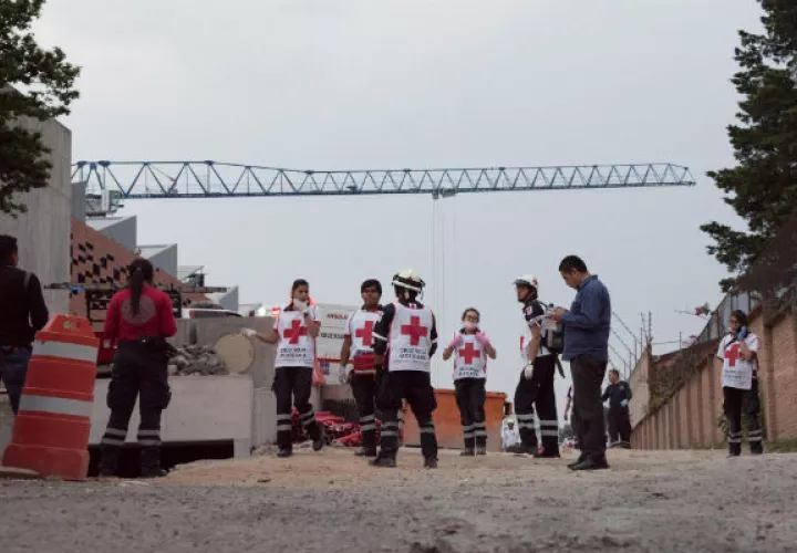 Integrantes de la Cruz Roja llegan al lugar donde un derrumbe en un estacionamiento en construcción. FOTO/EFE