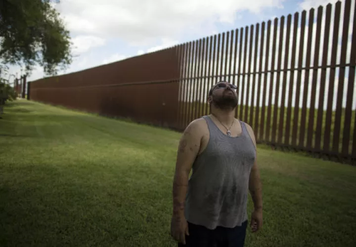 Antonio Reyes, de Brownsville, Texas, se encuentra junto a la cerca fronteriza de EE.UU. y México cerca de su casa. FOTO/AP
