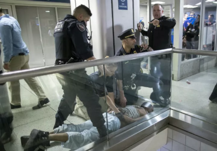 Los agentes de policía de la ciudad de Nueva York detienen a un pasajero que se convirtió en beligerante y provocó una estampida. FOTO/AP