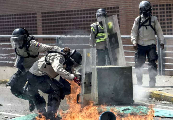 Un grupo de policías trata de protegerse de las bombas molotov. FOTOS/AFP