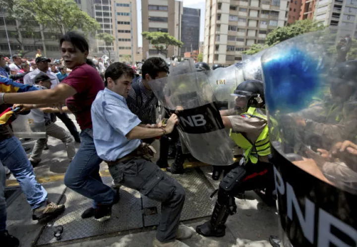 Un  grupo de manifestantes se enfrentan a los miembros de la policía. FOTO/AP