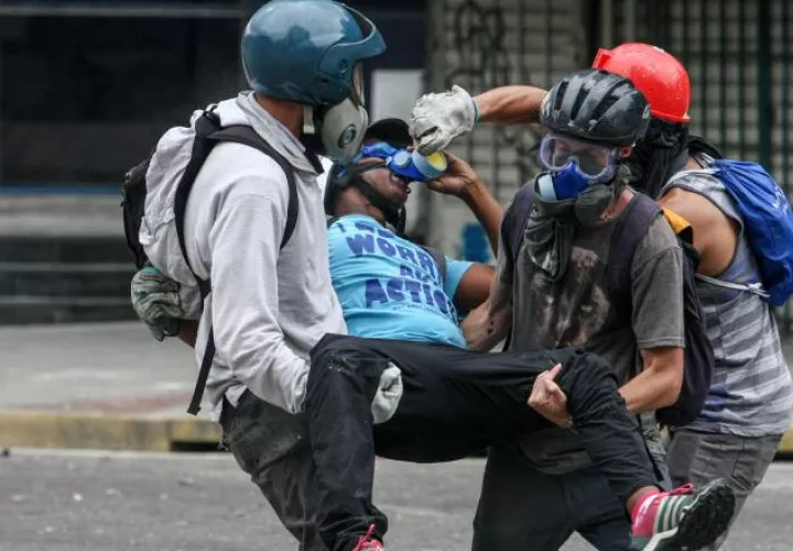 Manifestantes cargan a un compañero herido. /Foto efe