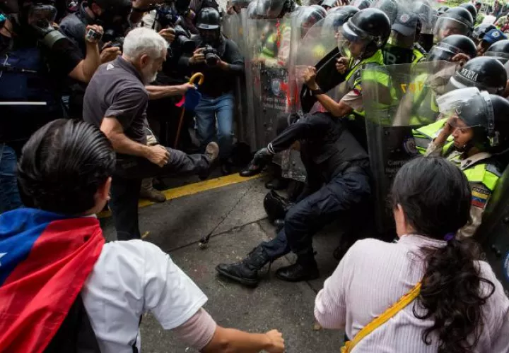 Manifestante golpea a policía. EFE