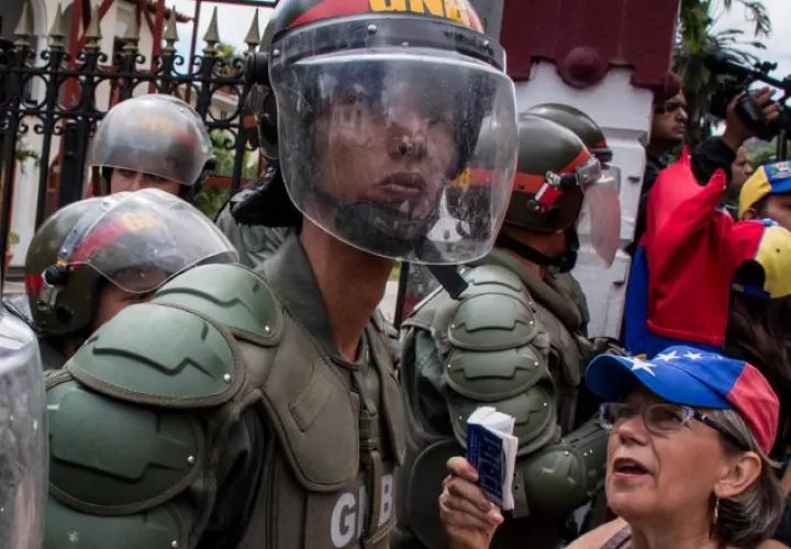 Una mujer enfrenta al policía. /Foto EFE