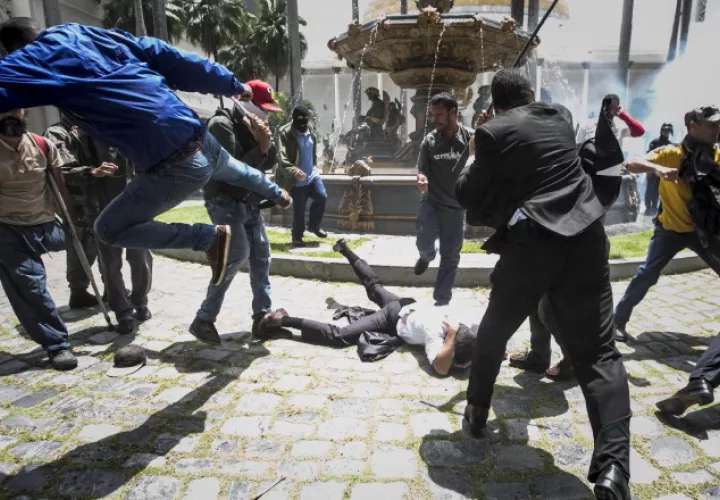 El diputado Armando Armas (c) es golpeado por manifestantes en el piso en la Asamblea Nacional . /Foto EFE