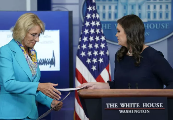 Sarah Huckabee Sanders, entrega el cheque de Donald Trump, a la secretaria estadounidense de Educación, Betsy DeVos. FOTO/AP