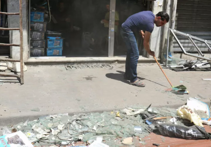 Un hombre recoge los cristales rotos cerca de su propiedad luego de la explosión. FOTO/AP