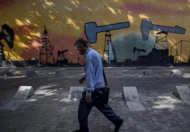 Un hombre camina frente a un mural en Caracas con diseños de la industria petrolera venezolana. EFE