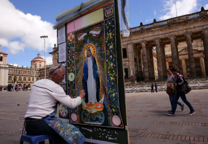 Diego Arcila Grajales da las últimas pinceladas al cuadro de la Virgen de la Medalla Milagrosa. FOTO/EFE