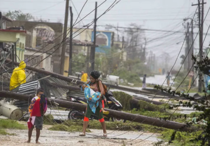 Una mujer entre postes derribados por Irma en Caibarien, Cuba. Foto: AP. 