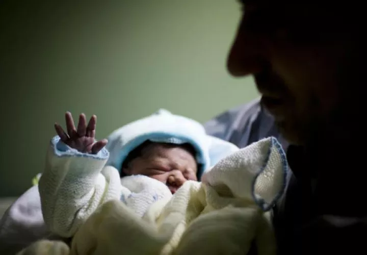 Un hombre sostiene a su hijo recién nacido.