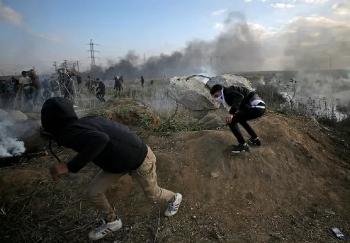 Unos jóvenes palestinos corren para resguardarse de los ataques. Fotos: EFE  