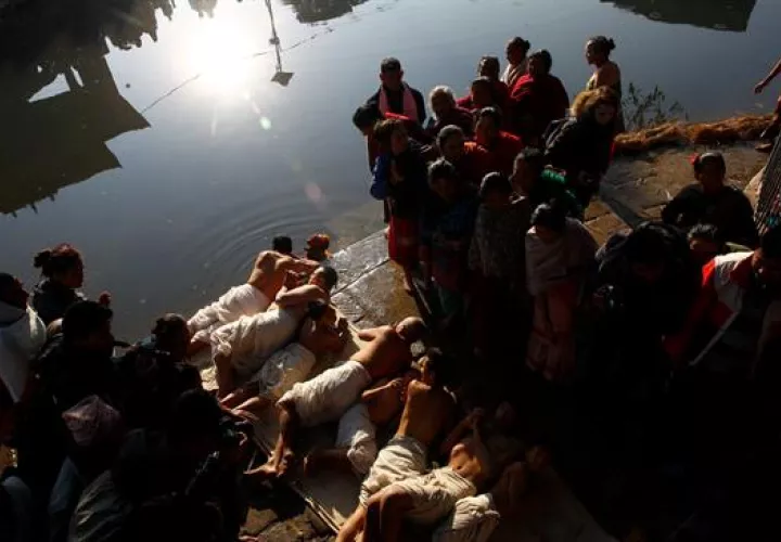 Devotos hindúes de Nepal ruedan en el suelo antes de tomar el baño. Foto: EFE