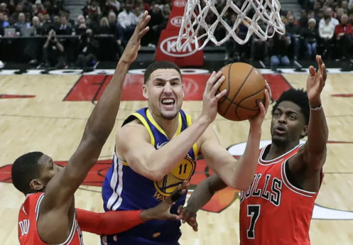 Klay Thompson  de los Warriors (cent.) anota una canasta ante el acecho de Kris Dunn (32) y Justin Holiday de los Bulls. Foto:AP